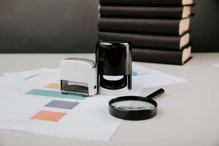 A plastic rubber stamp and charts on a wooden desk. Office accessoriesの写真素材