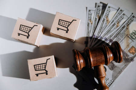 Consumer rights concept, judge gavel with dollar banknotes and card boxes on a table. Top viewの写真素材