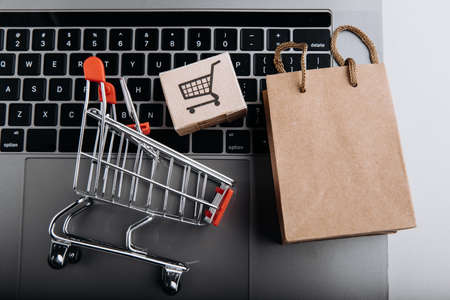 Cardboard boxes with a cart and shopping bag on a laptop close-up. Shopping service on the online webの写真素材