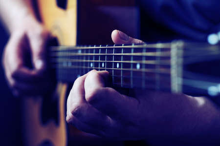 Hands playing acoustic guitar, close up