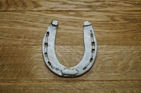 Old iron rusty metal horseshoe on weathered wood plank backgroundの写真素材