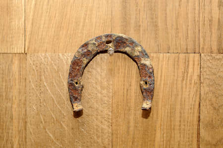 Old iron rusty metal horseshoe on weathered wood plank backgroundの写真素材