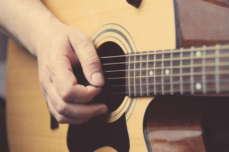 Man playing acoustic guitar at home, hand close-up.の写真素材