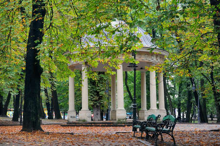 Park bench in the autumn on a background of white archesの写真素材
