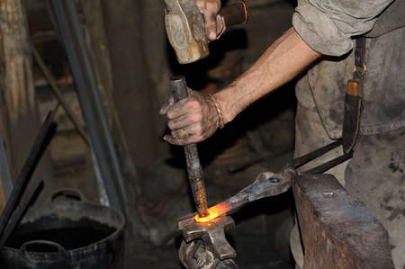 Blacksmith working on metal on anvil at forge high speed detail shot