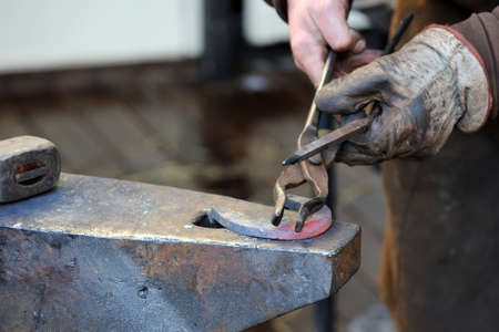 Blacksmith forges a horseshoe for horse