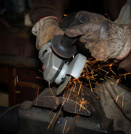 Heavy industry worker cutting steel with angle grinder