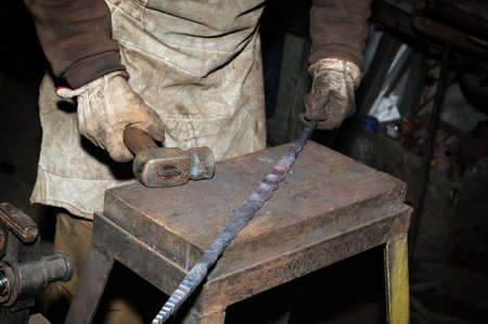 Blacksmith working metal with hammer on the anvil in the forge