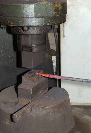 Blacksmith hammering hot iron automatic hammerの写真素材