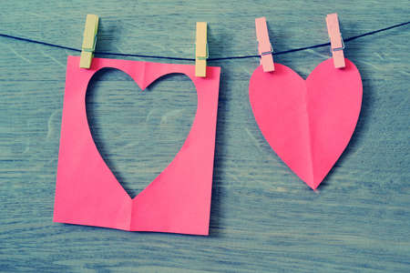 Red paper heart hanging on the clothesline. On old wood background.の写真素材