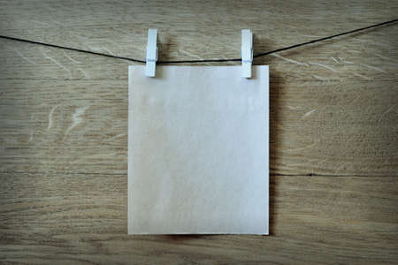 clothespin hanging with blank paper on wooden background