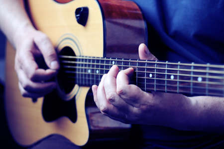 Hands playing acoustic guitar, close up