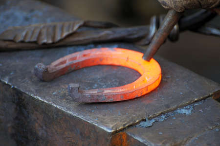 Blacksmith forges a horseshoe in a smithyの写真素材