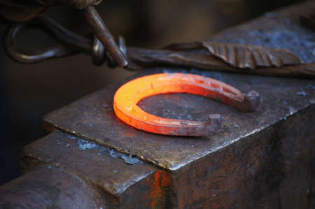 Blacksmith forges a horseshoe in a smithyの写真素材