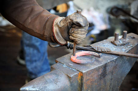 Blacksmith forges a horseshoe in a smithyの写真素材