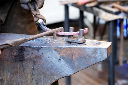 Blacksmith working metal with hammer on the anvil in the forge