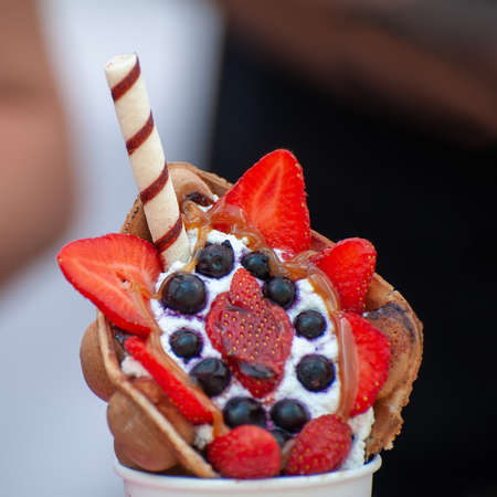 Cup with delicious sweet bubble waffle on dark  background