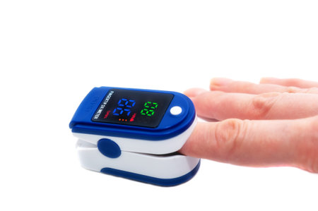 Pulse oximeter used to measure pulse rate and oxygen levels. Close up of Finger in an Oximeter Device. Pulse oximeter on white background.の写真素材