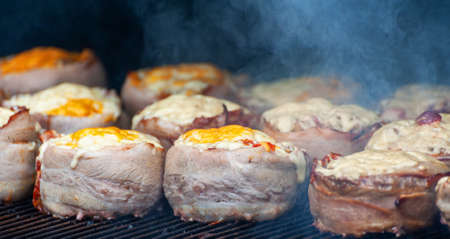 Cooking meatballs covered with bacon on the grill of barbecueの写真素材