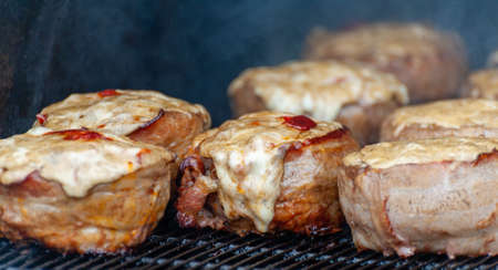 Cooking meatballs covered with bacon on the grill of barbecueの写真素材
