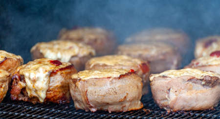 Cooking meatballs covered with bacon on the grill of barbecueの写真素材