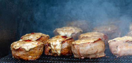 Cooking meatballs covered with bacon on the grill of barbecueの写真素材