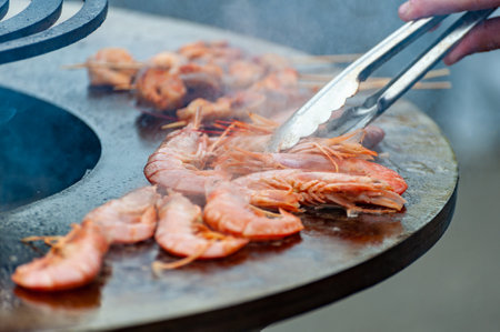 Street food festival, chef cooking delicious shrimps on a spit, outdoor seafood cooking on grillの写真素材