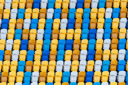 Blurred sitting fans colored plastic chairs at the football stadium background. Closeup of yellow and blue seats on stadium. ArenaLviv Ukraine.の写真素材
