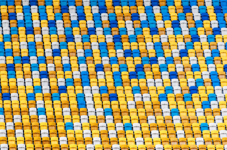 Blurred sitting fans colored plastic chairs at the football stadium background. Closeup of yellow and blue seats on stadium. ArenaLviv Ukraine.の写真素材