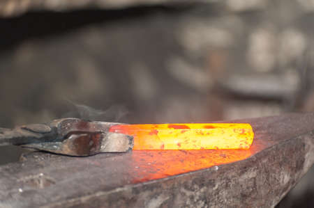 Blacksmith working metal with hammer on the anvil in the forge