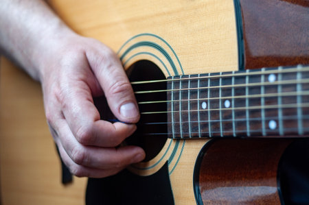 The musician plays the acoustic guitar. Musician's hand close-up.の写真素材