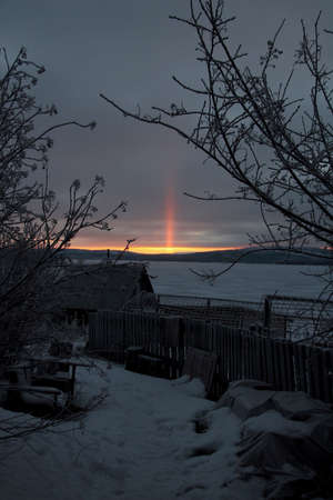 light pole in the North of Russia behind the lake from behind the mountainsの写真素材
