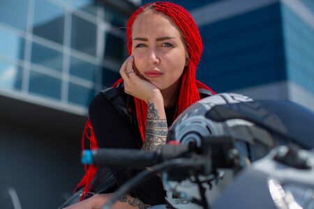 A beautiful woman on a motorcycle leans her face in her handの写真素材