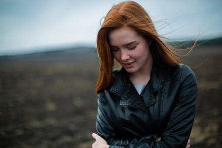 Red-haired beauty embraces herself with downcast eyes.の写真素材