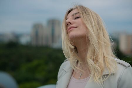 A dreamy blonde is sleeping on the roof, turning her face to the wind.の写真素材
