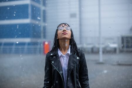 Young rebel stands in the pouring rain.の写真素材