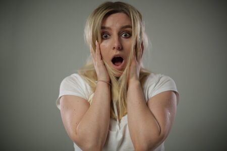 A blonde girl poses in the Studio with a surprised faceの写真素材