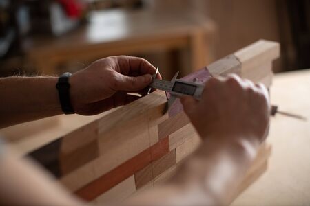 Hands of a carpenter measure the logs of wood with the help of Vernier caliper.の写真素材