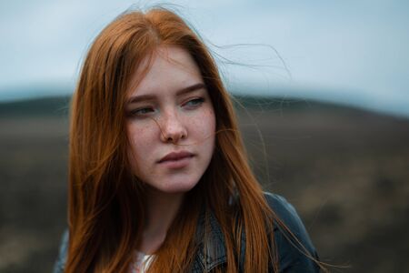 The sad red-haired woman looks longingly into the distance.の写真素材