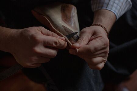 The hands of the shoemaker at work make the sole for new handmade shoes.の写真素材