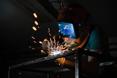 The welder works with a welding arc over a metal structureの写真素材