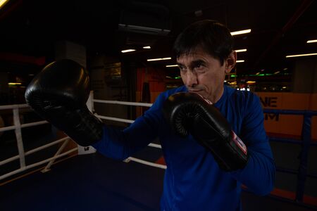A boxing coach stands in the ring wearing black gloves ready to spar. Concept of sports motivationの写真素材