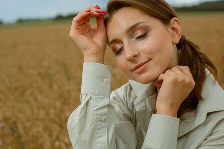 Portrait of a lovely pleasant woman who holds her hair with her hand, which is blown by the wind. She stands on the roof and smiles.の写真素材