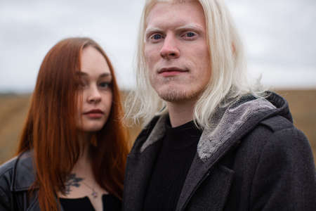 Portrait of a young couple with an interesting appearance. A young male albino with a massive chin...