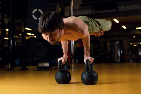 The man performs a complex acrobatic trick - horizontal rack on weights. Focus on sports. Concentration during exercise.の写真素材