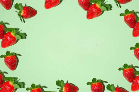 frame with red juicy strawberries on a green background. Fruit print. Summer bright juicy photo. Photo for printing, banner, fabric. High quality photoの写真素材