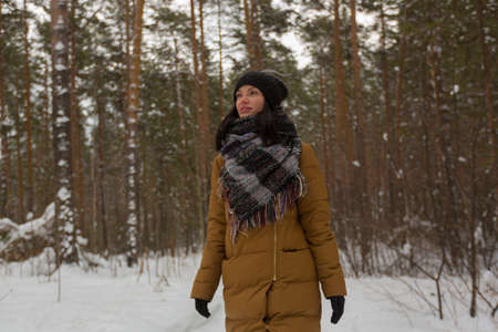 a young girl in a black hat and a brown jacket walks through the winter snow forest. Winter forest. Winter landscape. High quality photoの写真素材
