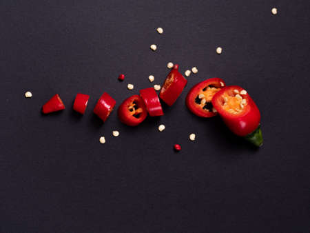 hot red chili pepper lies on a black background, a small pod cut into many pieces. Cook at home. High quality photoの写真素材