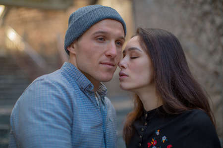 a young couple in love guy and girl stand on the street near the stairs, the rays of the sun fall on...