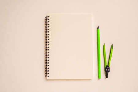 school layout: bright green pencil and compass, beige notebook neatly laid out on a beige...